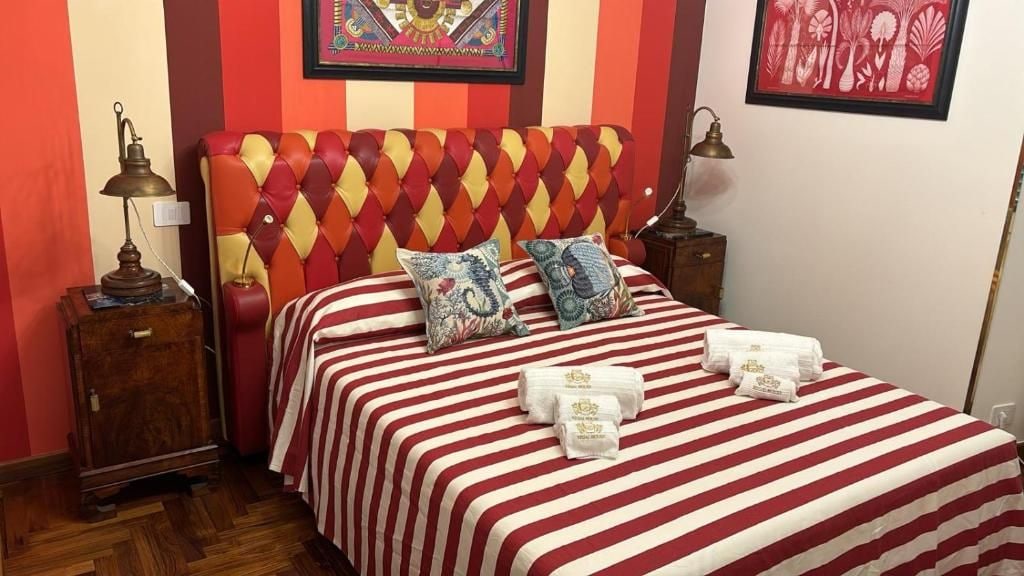 Una habitación de hotel con una colcha a rayas, un cabecero capitonado y dos lámparas de noche.