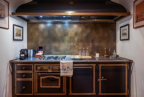 A kitchen with a stainless steel backsplash, a gas stove, a coffee maker, and a sink.