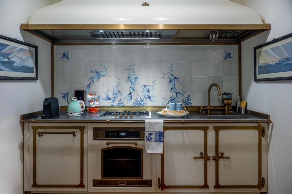 A kitchen with a tiled backsplash, a stove, a coffee maker, and a clock.