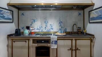 A kitchen with a tiled backsplash, a stove, a coffee maker, and a clock.