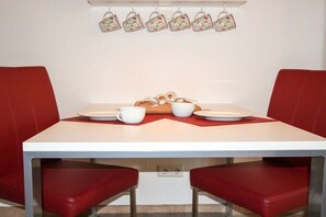 Une table à manger avec deux chaises, un service de vaisselle, des tasses et un panier à pain.