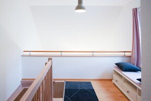 A room with a wooden staircase, a window with a view, a bed with a pillow, and a ceiling light. - Holiday home in Zingst with swimming pool (Zingst)