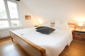 A bedroom with a single bed, bedside tables, a window, and a radiator. - Holiday home in Zingst with swimming pool (Zingst)