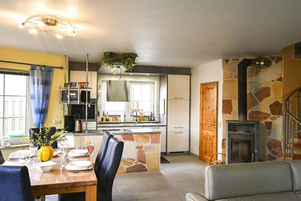 A modern kitchen with a stone accent wall, a dining area with a table set for two, and a fireplace.