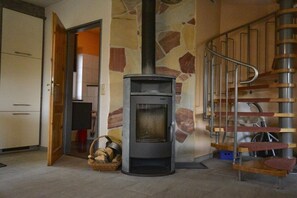 Ein Zimmer mit Steinsandsteinwand, Kamin, Treppe und einer Tür zu einem anderen Raum.