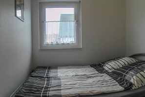A small, single-bed room with a window and a view of buildings outside. - Swan in the house at the sweetling (Glowe)
