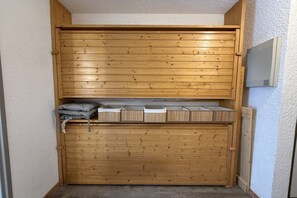 Un mueble de almacenamiento de madera con varios compartimentos, que incluye un estante inferior con objetos doblados y un estante superior con cajas.