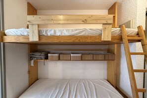 A bunk bed with a wooden frame, a ladder, and storage compartments. - Mountain View Apartment in Modane (Modane)