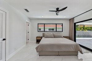 Ein Schlafzimmer mit einem Bett, einem Deckenventilator, einem Fenster mit Ausblick und einer Tür.