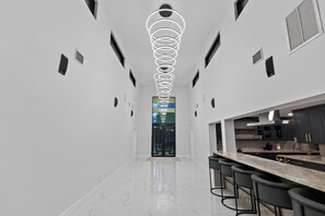 A modern kitchen with a marble countertop and bar stools. - AVAIALBLE Boat Show FLIBS ! 2 mins to Broward Convention Center!  5BR + Dock! (Fort Lauderdale)
