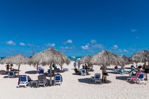 A beach with thatched umbrellas and sun loungers. - Luxury apartment with double sea view and pool. (Punta Cana)