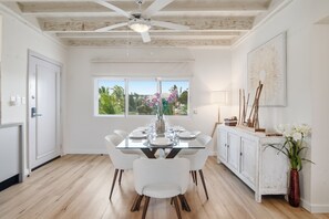 A dining area with a glass table, white chairs, and a view of greenery outside. - Luxury apartment with double sea view and pool. (Punta Cana)