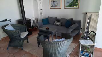 A living room with a sofa, two wicker chairs, a coffee table, a fireplace, and a radiator.