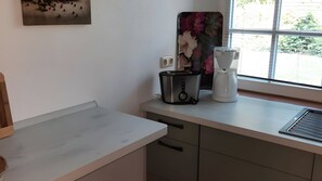 A kitchen with a toaster, a coffee maker, and a window with a view of greenery.