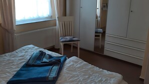 A hotel room with a bed, a chair, a wardrobe, and a window with curtains. - Apartment 'Zempin Seebad, Dorfstraße 20' with Wi-Fi (Zempin (Seebad))