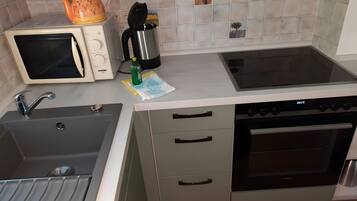 A compact kitchen with a microwave, stove, sink, and oven.