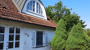 A white building with a brown tiled roof, white shutters, and a number '20' on the wall.