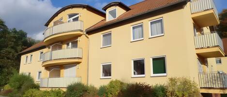 A multi-story residential building with balconies, windows, and a garden area.