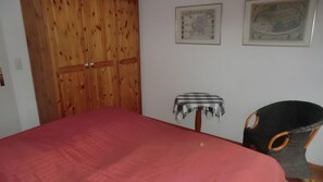 A room with a bed, a wooden wardrobe, a small table with a cloth, and a chair. - Apartment 'Koserow Seebad, Waldstraße 14' with Balcony and Wi-Fi (Koserow)