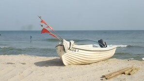 A boat with a flag on a sandy beach with the sea in the background. - Apartment "Koserow Seebad, Lindenstraße 18" with Private Terrace, Garden & Wi-Fi (Koserow (Seebad))