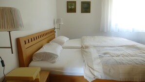 Een hotelkamer met een bed, nachtkastje, lamp en twee aan de muur hangende schilderijen.