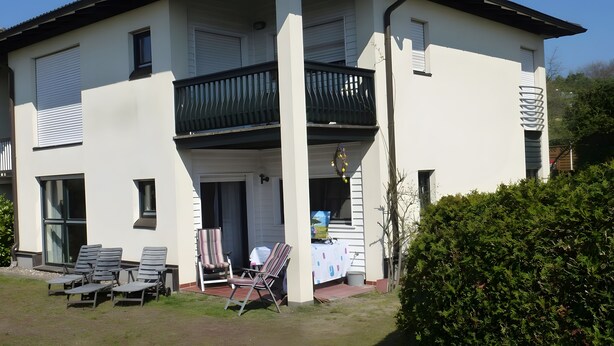 Een twee verdiepingen tellend huis met een balkon, buitenplaats en een tuin.