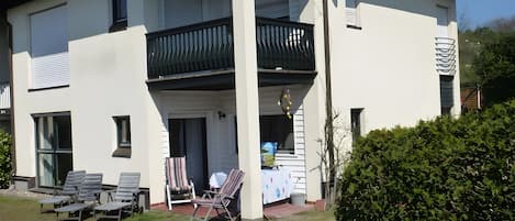 A two-story house with a balcony, outdoor seating, and a garden.