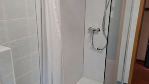 A shower area with a glass door, white tiled walls, and a showerhead mounted on the wall. - Apartment "Koserow Seebad, Lindenstraße 18" with Private Terrace, Garden & Wi-Fi (Koserow (Seebad))