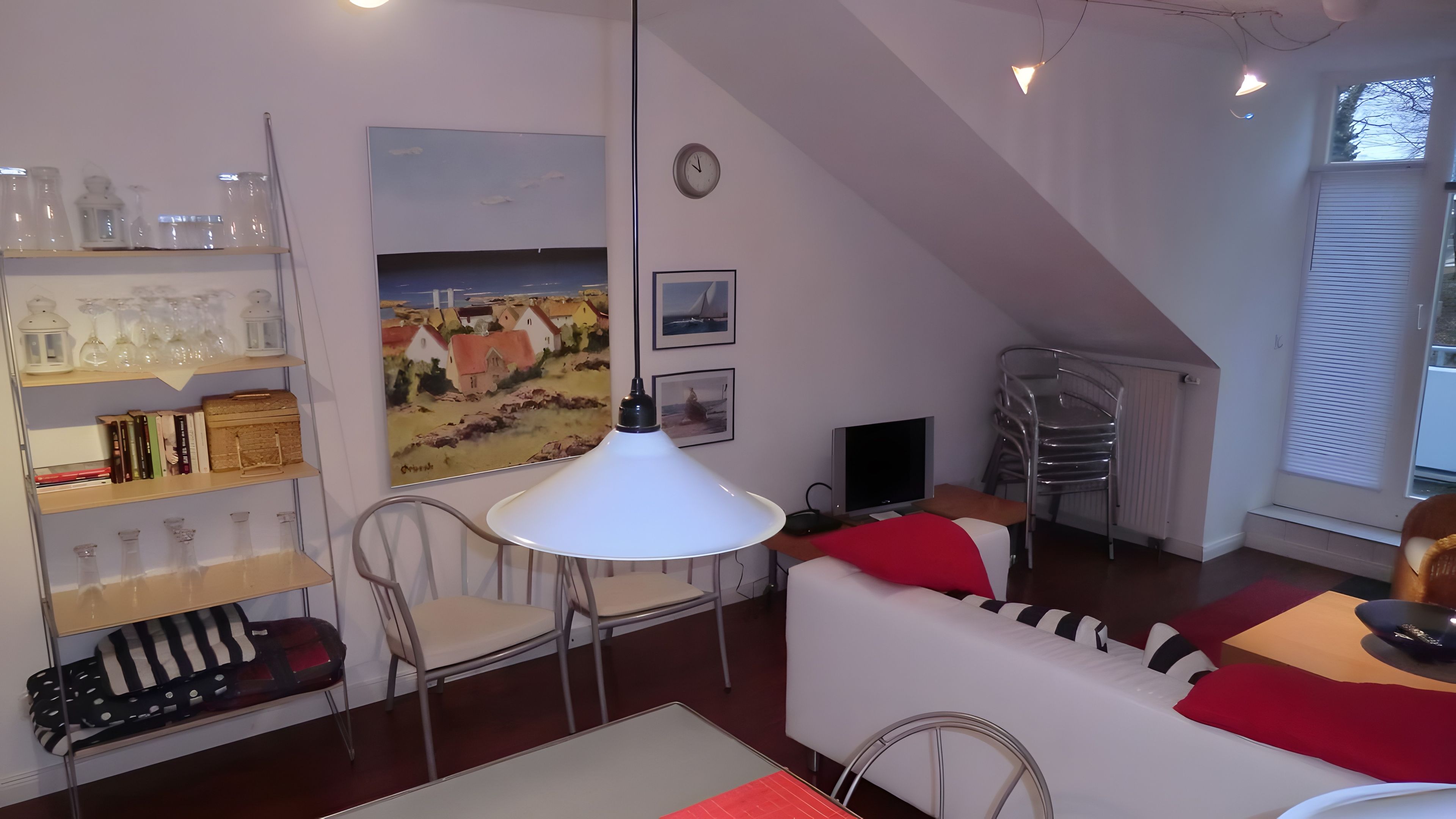 Een gezellige woonkamer met een witte bank, een eettafel en een boekenplank.