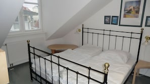 Ein Schlafzimmer mit schwarzem Metallbettgestell, weißer Bettwäsche, einem runden Holztisch und einer Heizung.