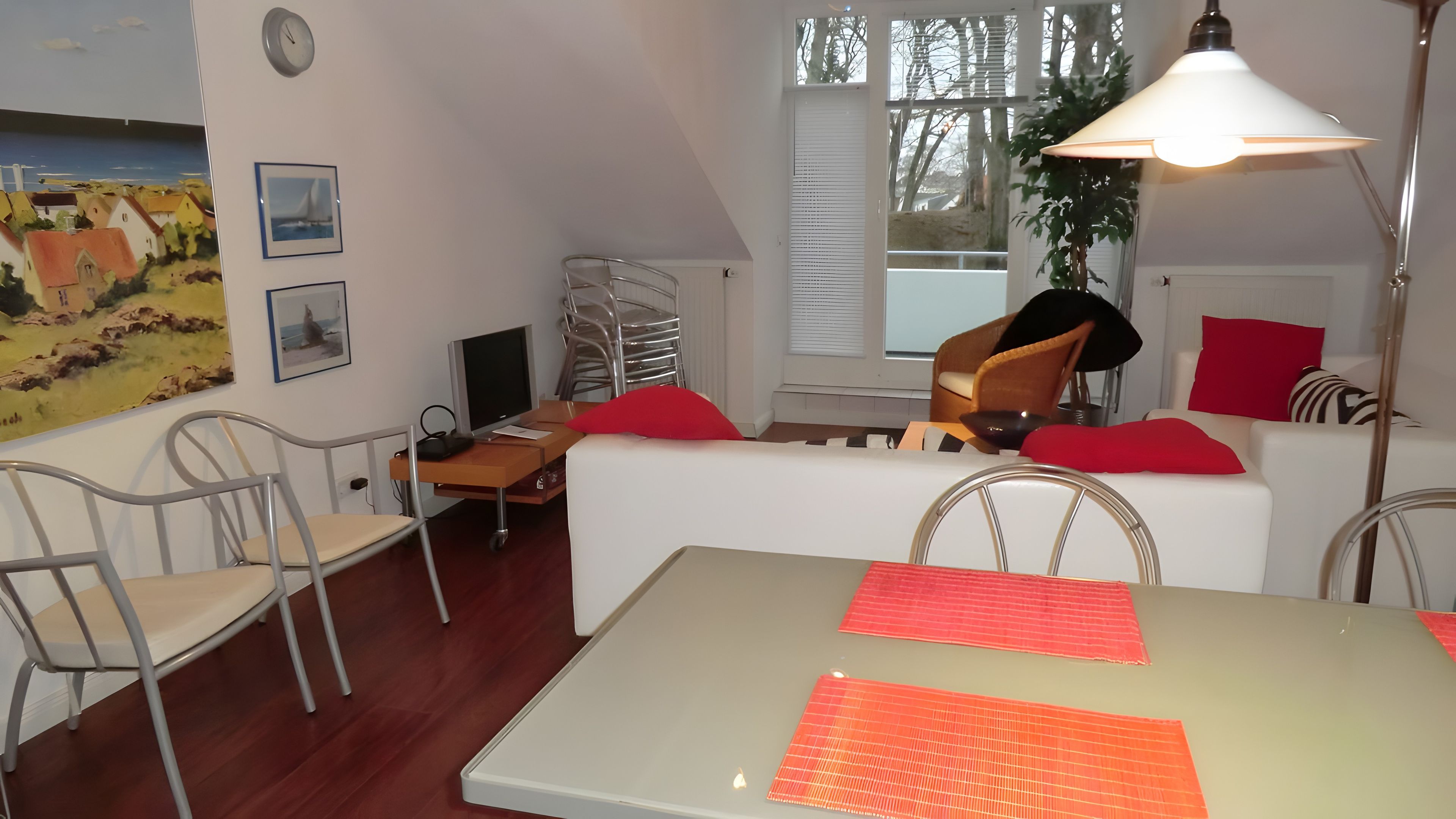Ein modernes Wohnzimmer mit Esstisch, einer Couch, einem Fernseher und einer Lampe.