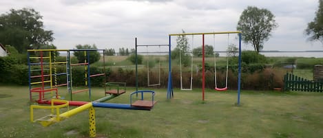 A playground with various play structures including a climbing frame, swings, and a seesaw.