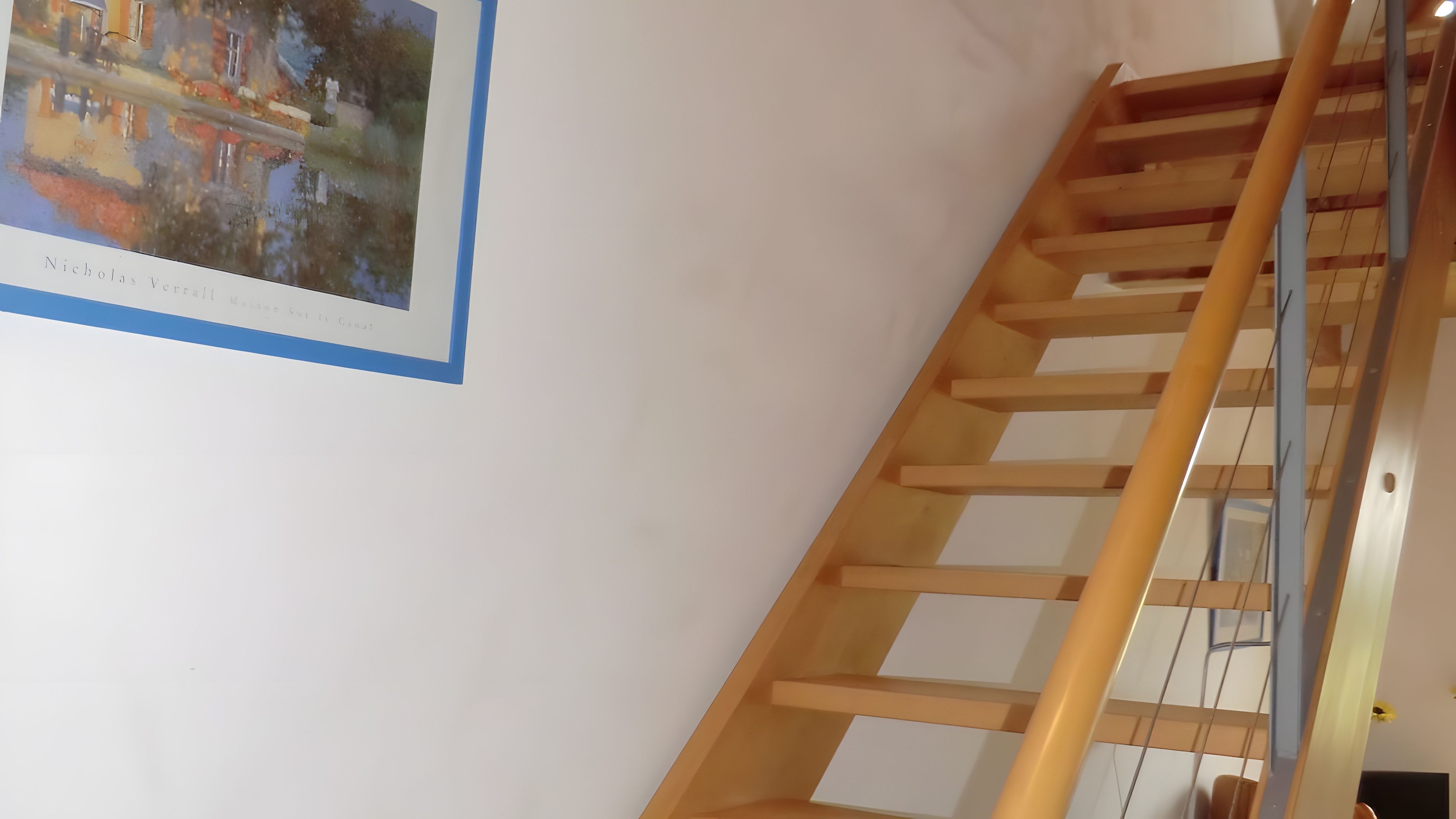 Una escalera de madera con barandilla y un borde azul, que lleva a un piso superior.