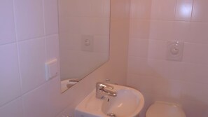 A bathroom with white tiles, a sink, a mirror, and a toilet. - Holiday Apartment 'Ferienwohnung Zinnowitz, Seestraße 3a WE 5' with Balcony & Wi-Fi, Near Beach, Central (Zinnowitz)