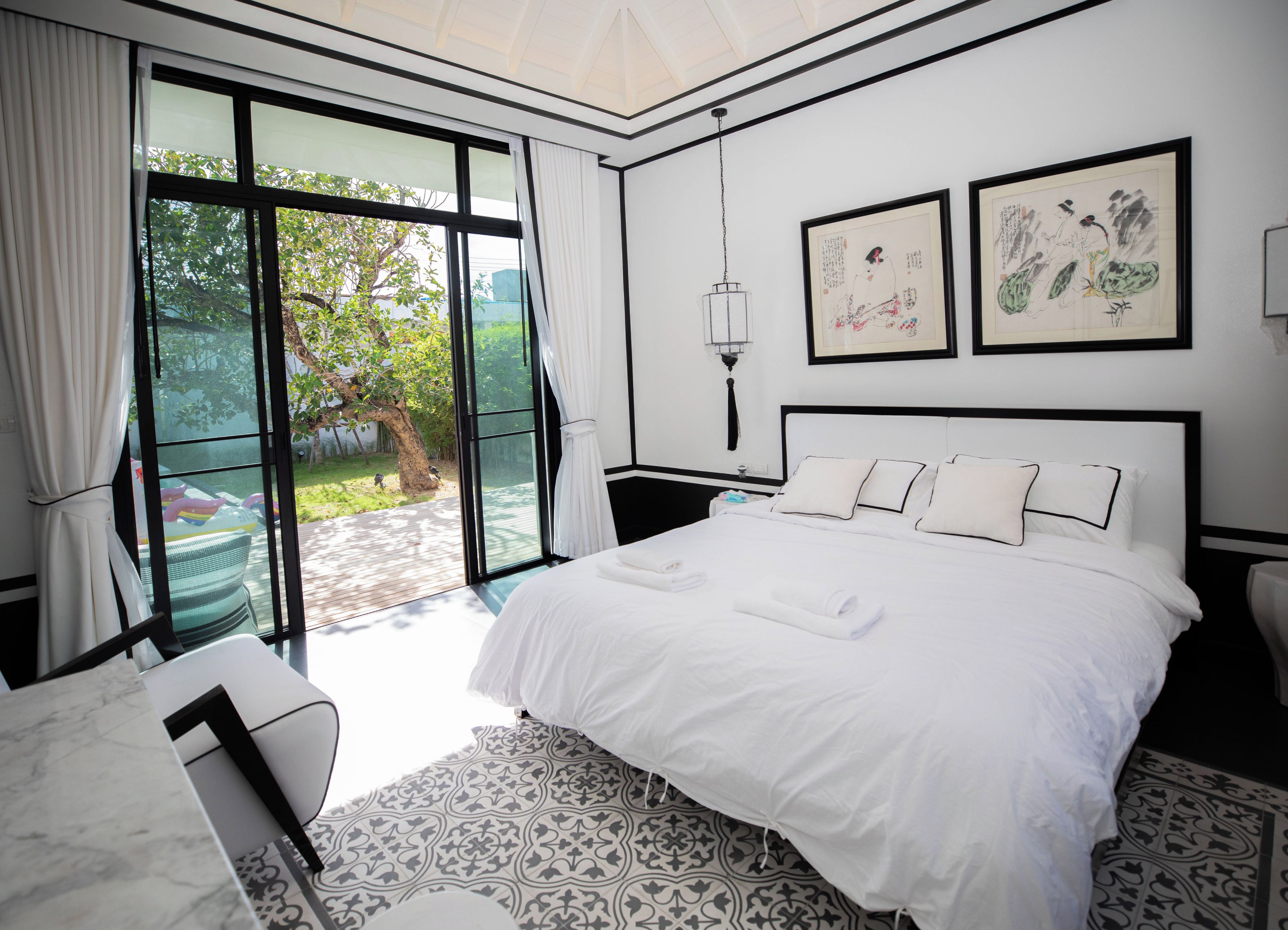 A hotel room with a large bed, a desk, a chair, and a view of the outdoors.