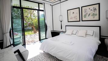 A hotel room with a large bed, a desk, a chair, and a view of the outdoors.