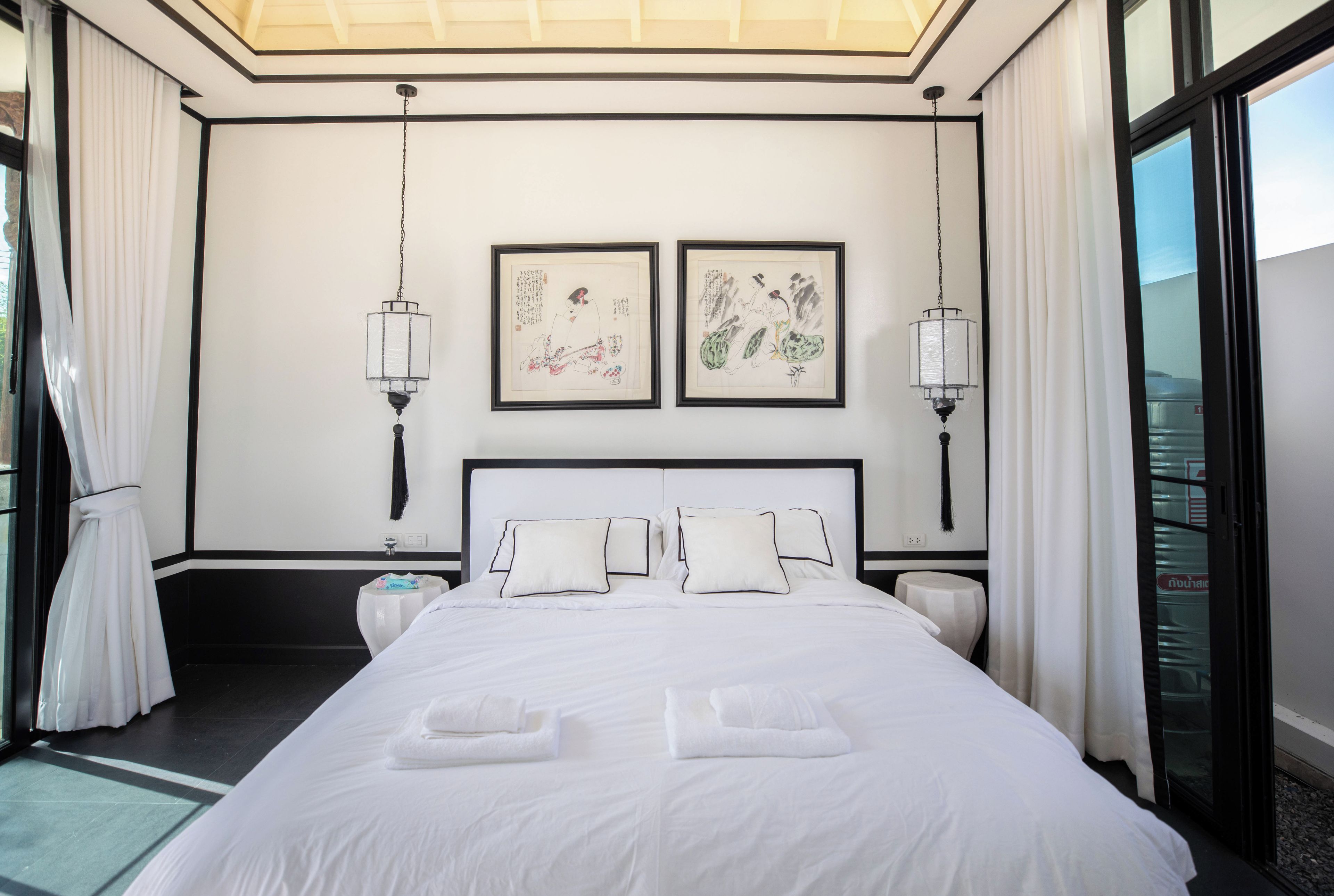 Une chambre d’hôtel avec un grand lit, deux lampes fixées au mur et des œuvres d’art.