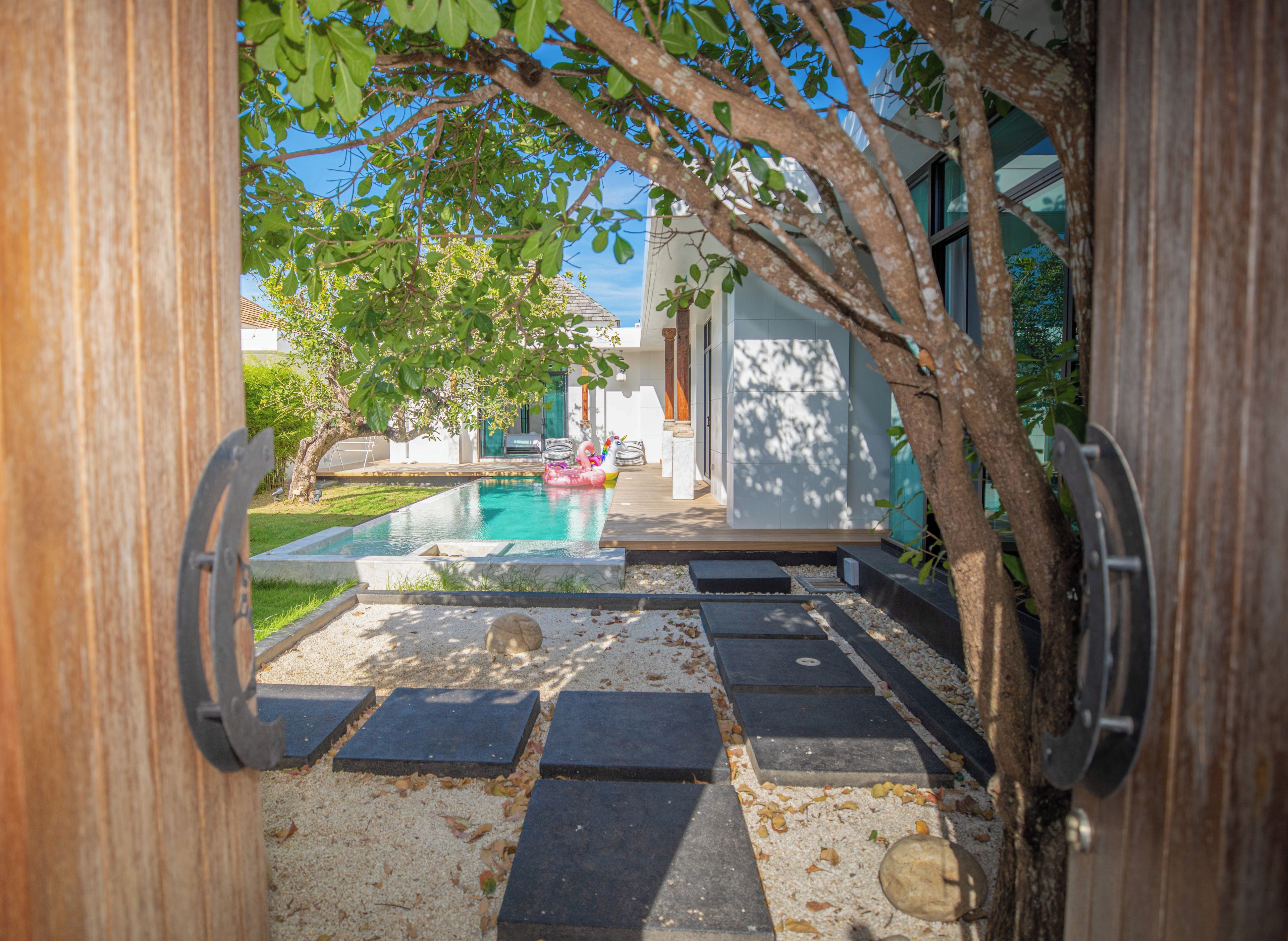 Zona de piscina con vistas despejadas del paisaje circundante, incluyendo un árbol y un edificio moderno.