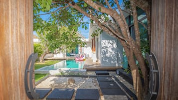 Zona de piscina con vistas despejadas del paisaje circundante, incluyendo un árbol y un edificio moderno.