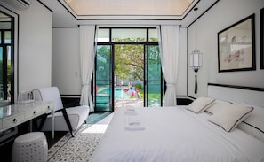 A hotel room with a bed, a desk, a chair, and a view of a swimming pool. - Chalong 3bed-room seaside pool villa  (Tambon Chalong)
