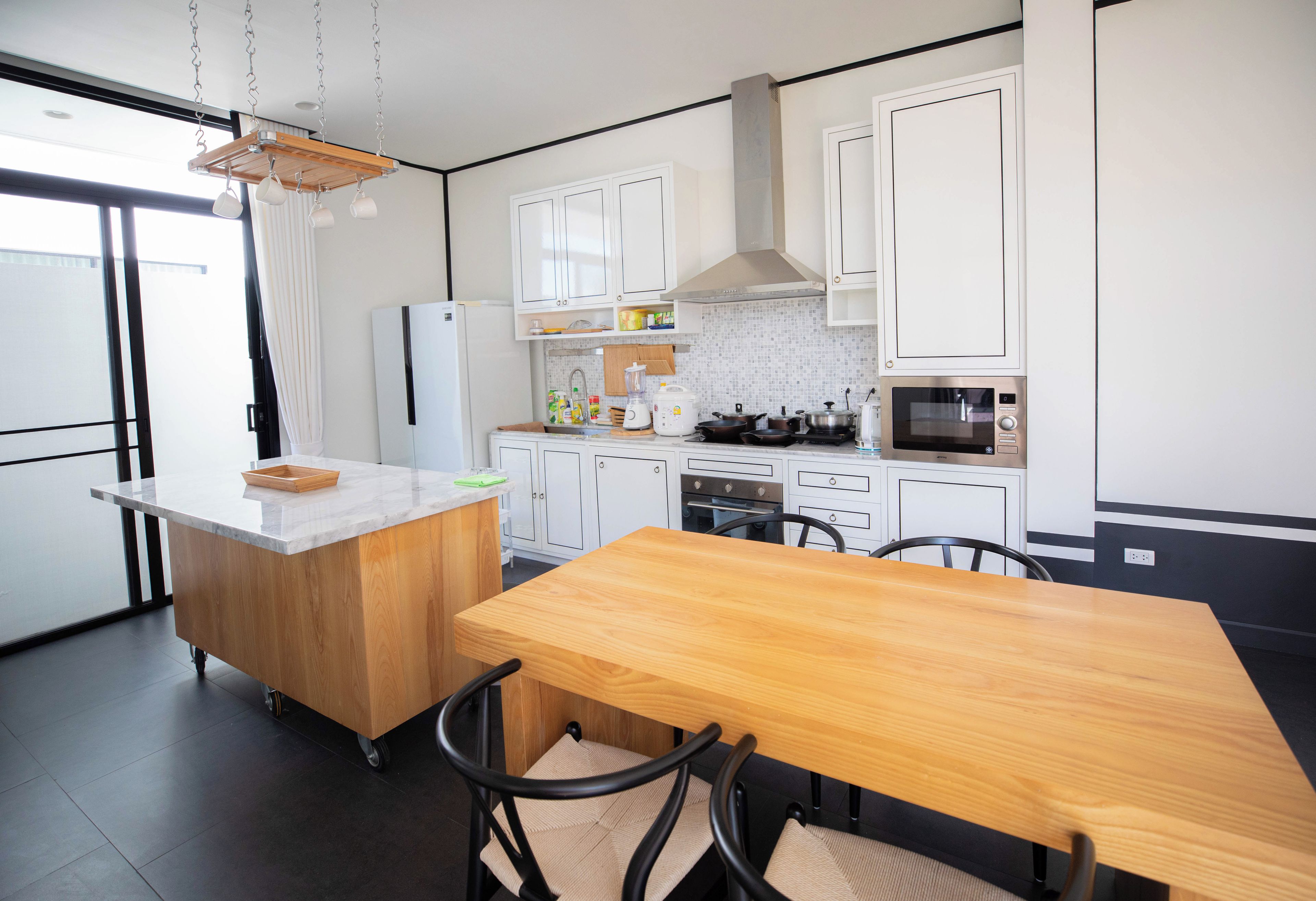 Een moderne keuken met een centraal eiland, witte kasten en een eettafel met stoelen.
