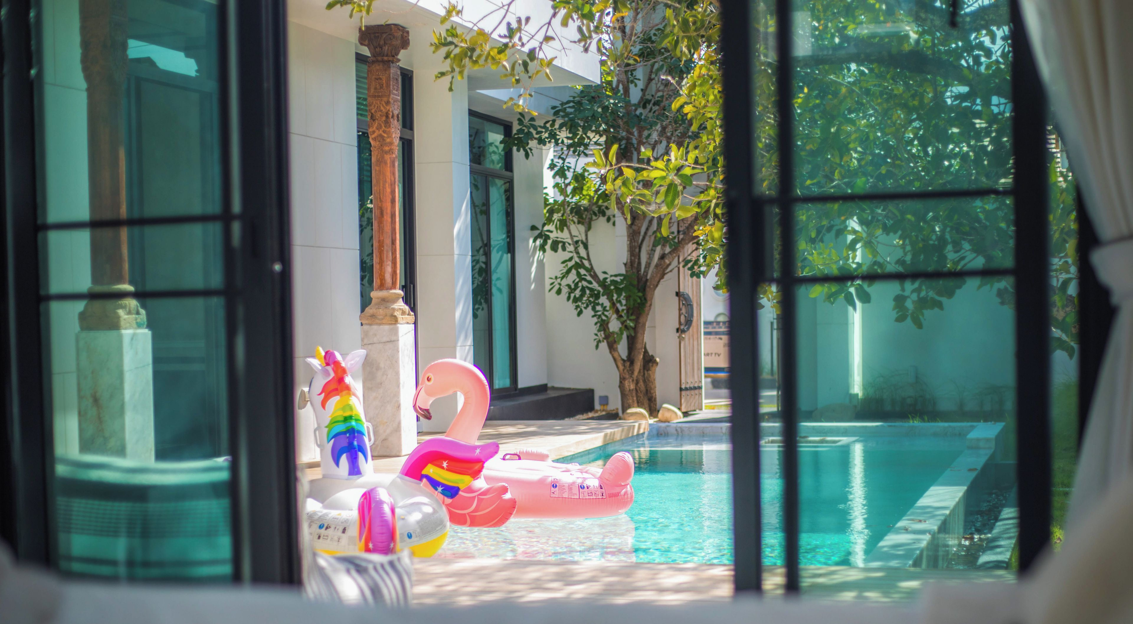 A pool with inflatable toys and a view of a building with columns.