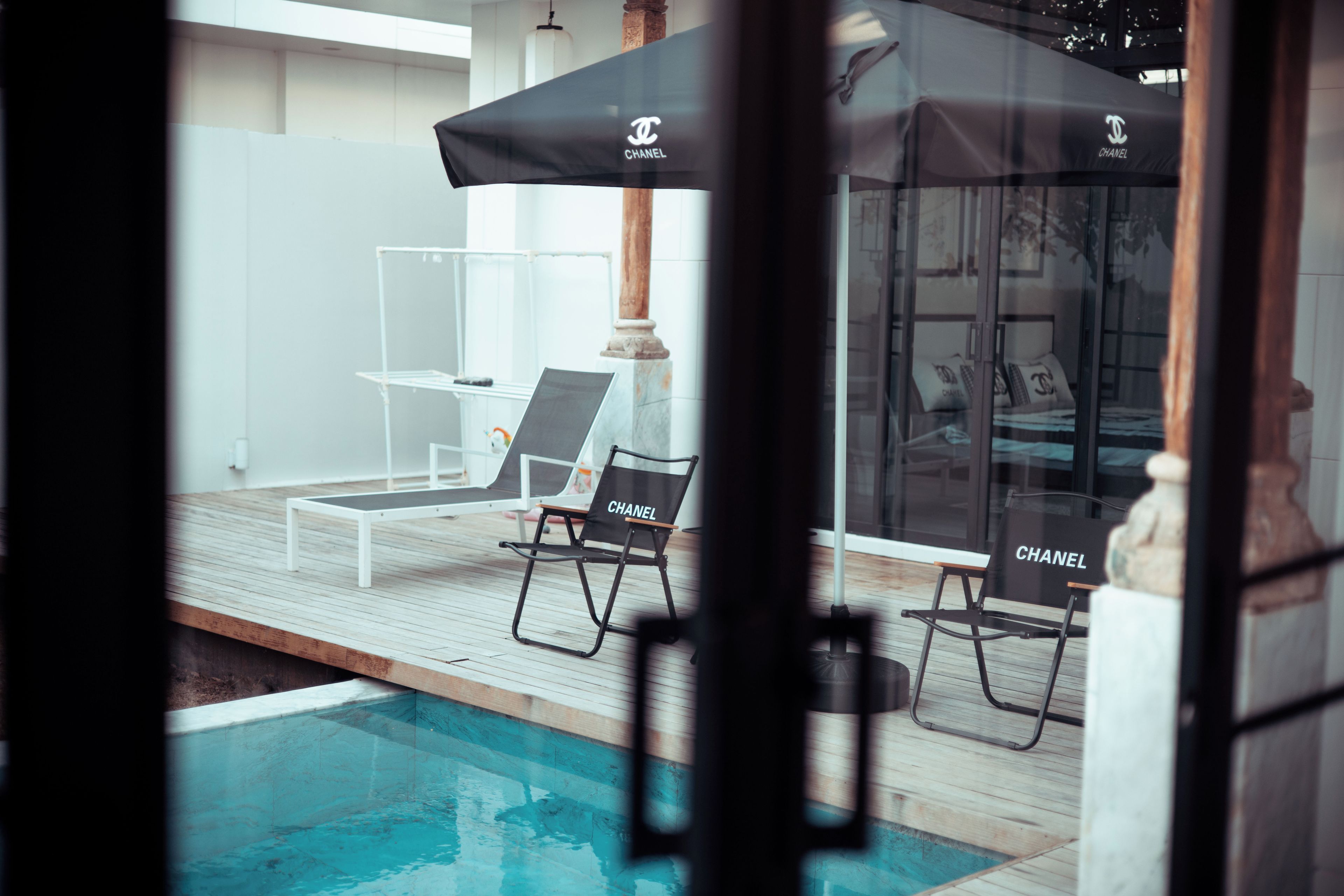 A poolside area with lounge chairs and umbrellas, a wooden deck, and a clear view of the pool.