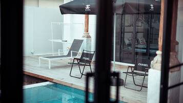 A poolside area with lounge chairs and umbrellas, a wooden deck, and a clear view of the pool.