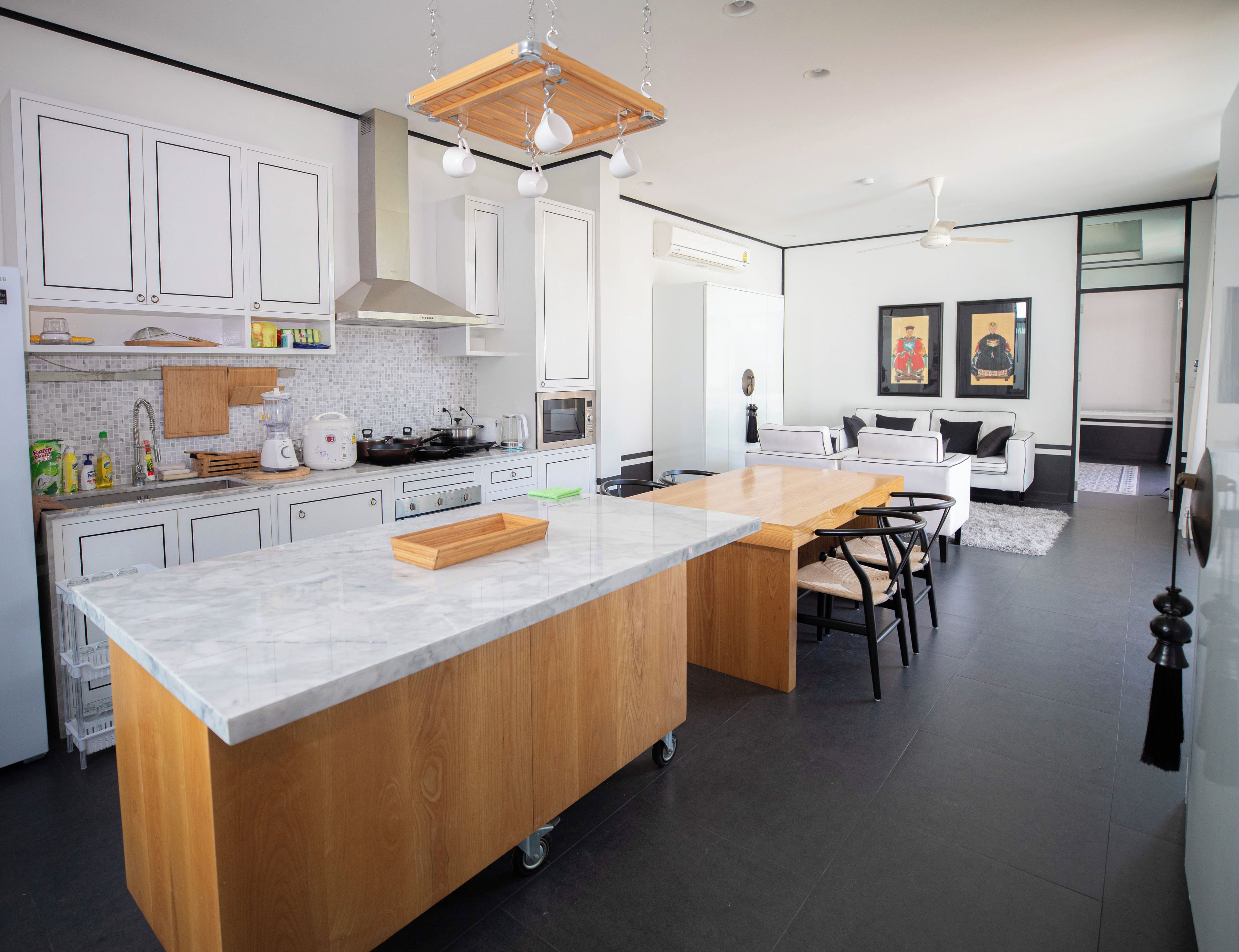 Een moderne keuken met een groot eiland, witte kasten en een zithoek met een bank en stoelen.