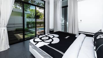 A modern bedroom with a large bed, a view of a garden, and a sliding glass door.