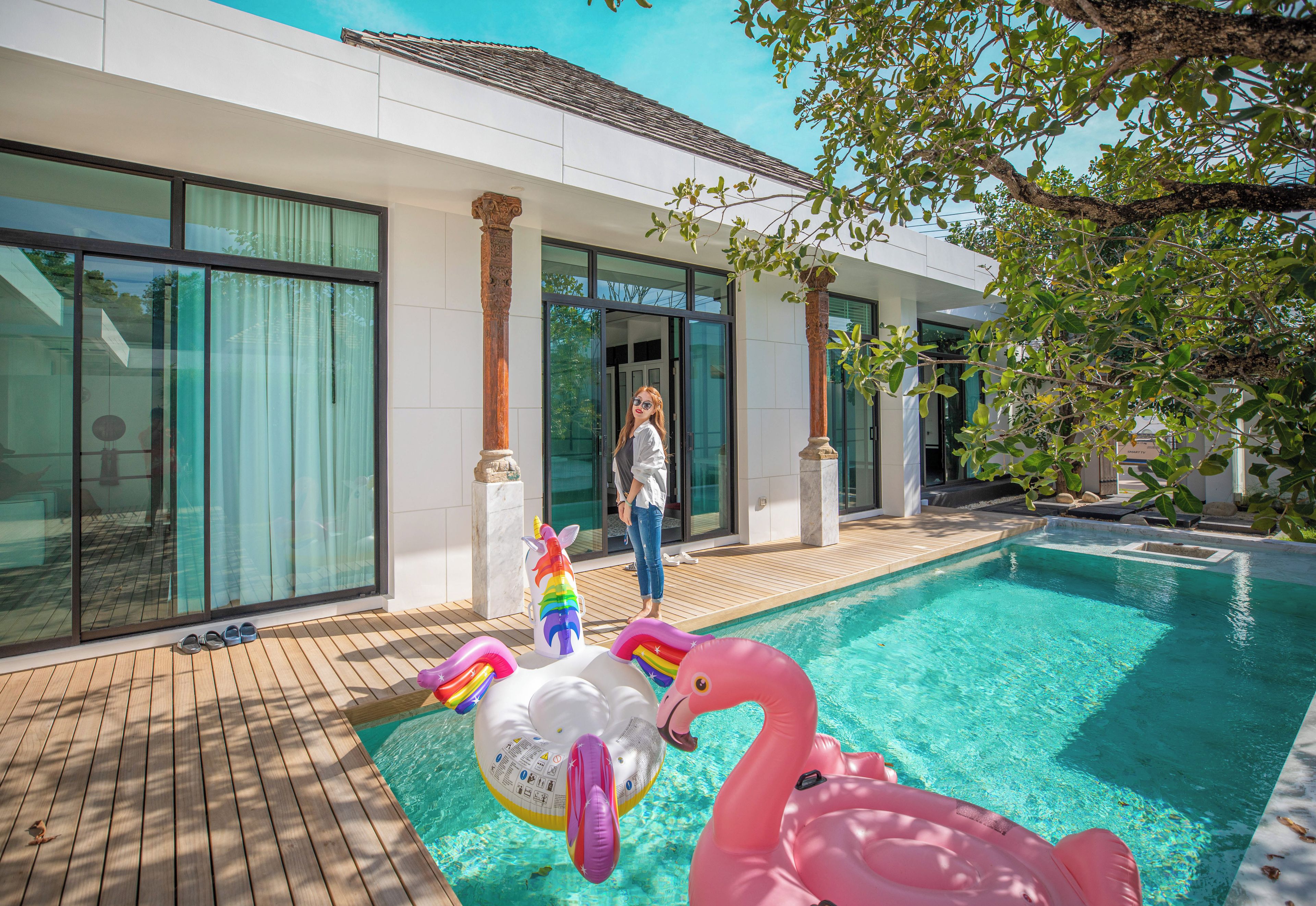 A swimming pool with inflatable toys and a person standing by the poolside.