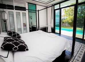 Et moderne soveværelse med en stor seng, et walk-in closet og udsigt til en swimmingpool.