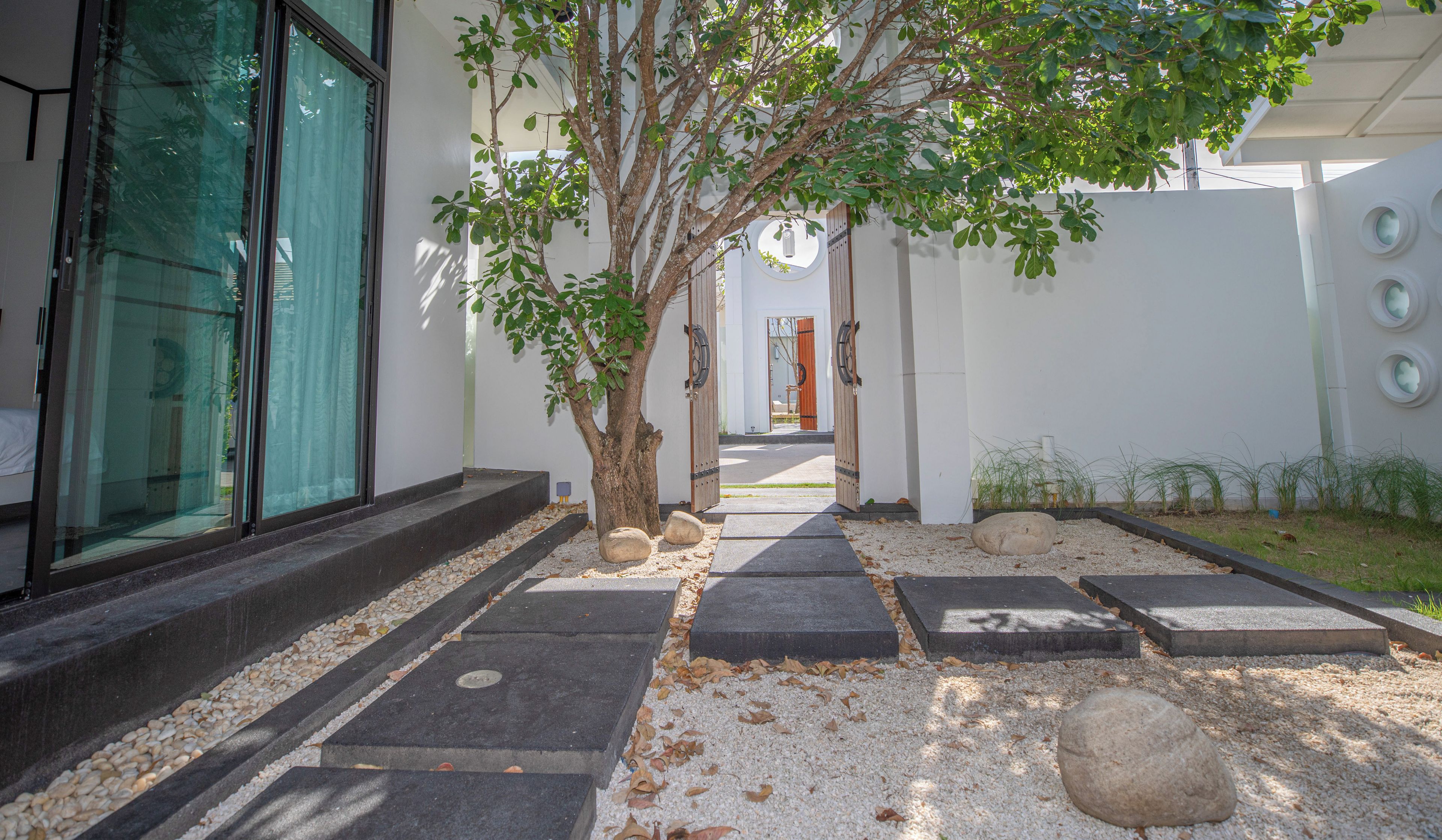 A pathway leading to a building entrance with a tree, steps, and a gravel area.