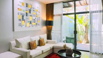 A modern living room with a white sofa, a red rug, a black coffee table with a vase, and a large window with curtains.